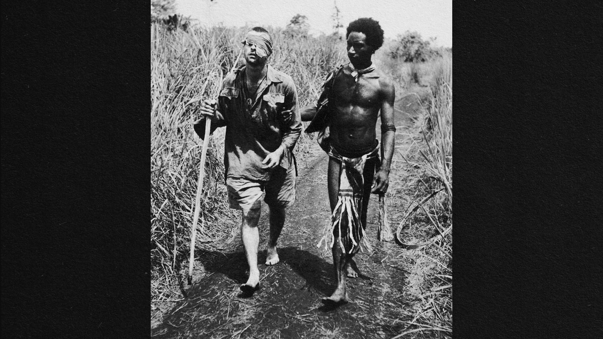 A black and white photo of two men walking down a path in Papua New Guinea.