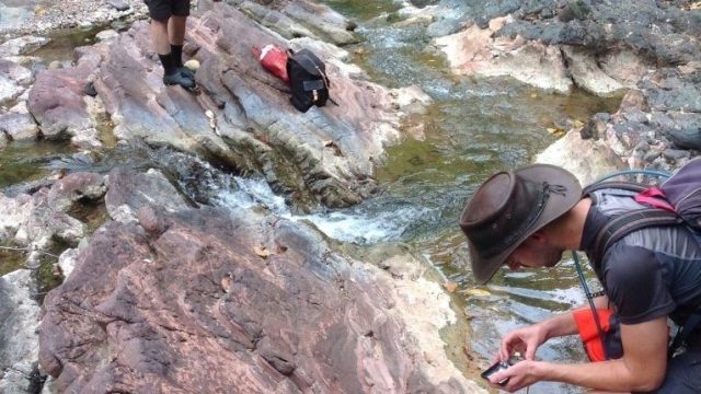 A group of hikers standing on rocks near a stream.