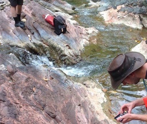A group of hikers standing on rocks near a stream.