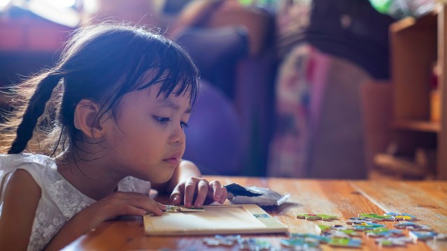 A child happily engaged in solving a large puzzle.