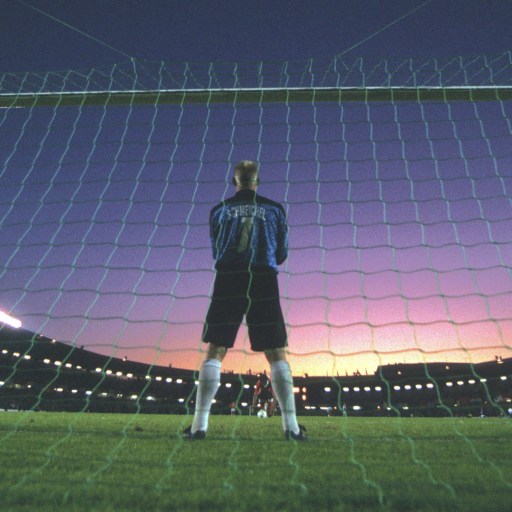 A soccer goalie displaying action and focus standing in front of a net.