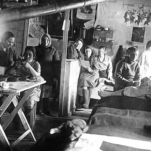 A group of people sitting around a table in a room, engaged in conversations amidst an air of exile.