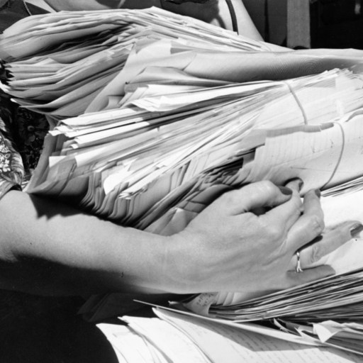 Black and white photo of a woman holding a stack of papers, illustrating Parkinson's Law.