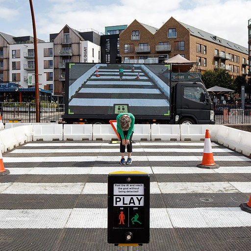 A man is crossing a street with cones in front of him.