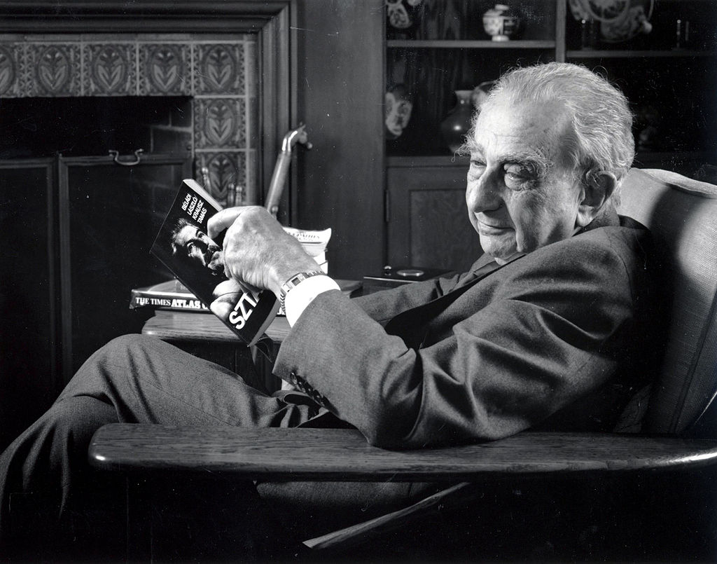 A man sitting in a chair reading a book.