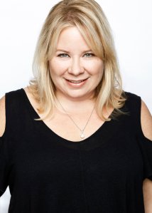 A blonde woman in a black top posing for a photo.