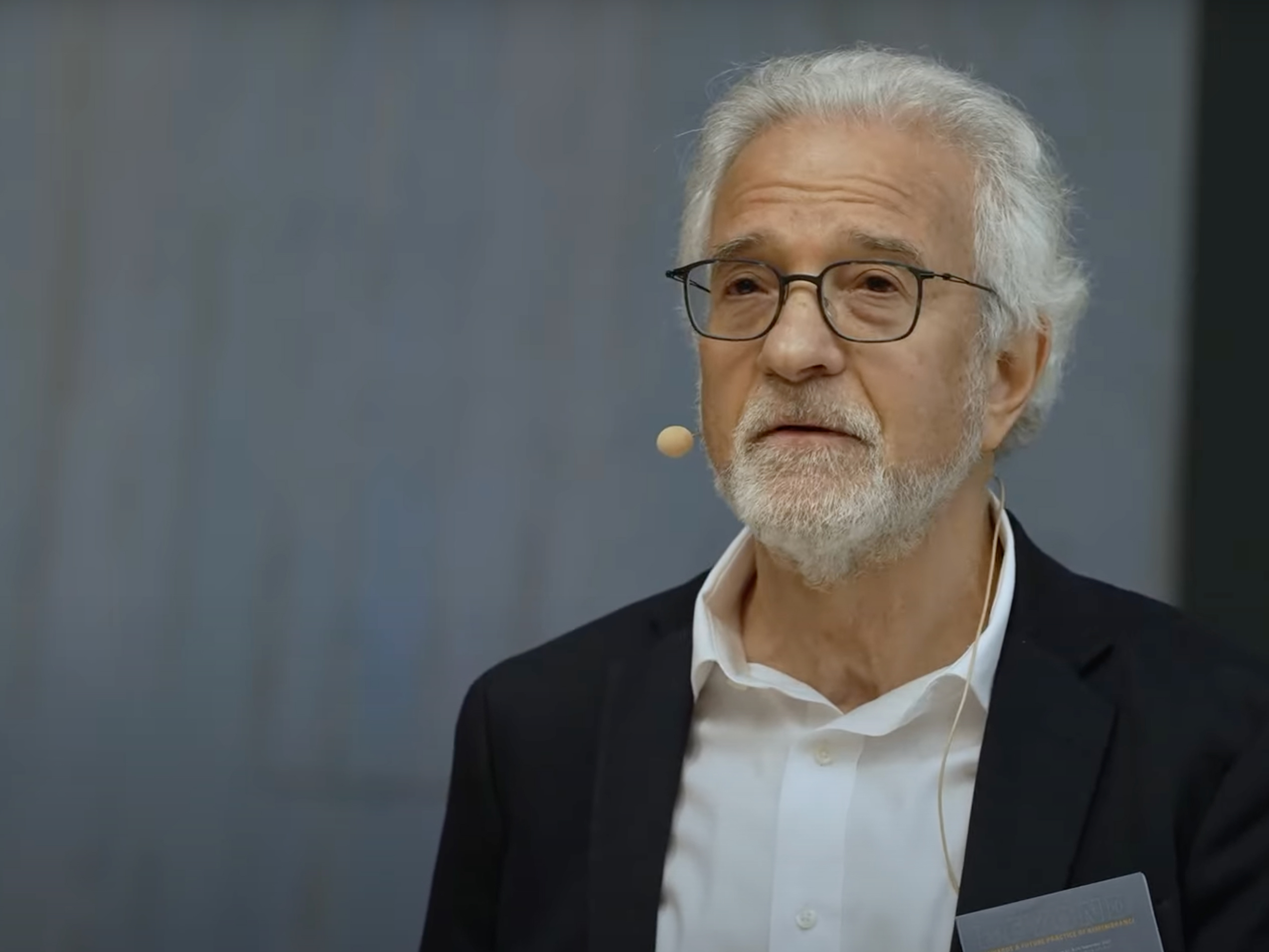 A man with glasses and a beard speaking into a microphone.