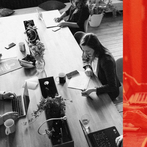 A group of people sitting at a table in a brave space, working on their laptops.