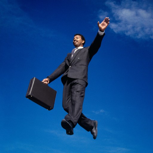 A man in a suit experiencing eudaimonic happiness while jumping in the air with a briefcase.