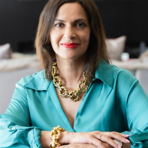 A woman wearing a blue shirt and gold necklace.