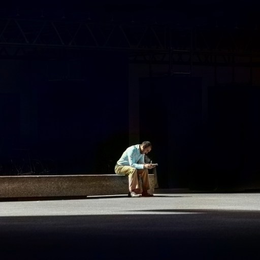 A man sitting on a bench in the dark.
