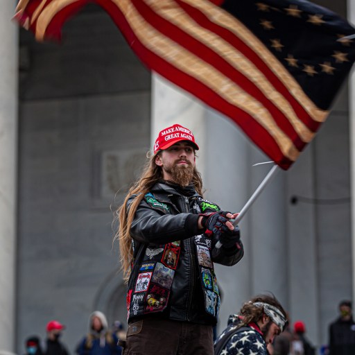 A man waving an american flag in front of a group of people.