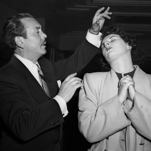 A man in a suit hypnotizing a woman.