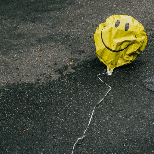 A yellow balloon lying on the ground in front of a car.