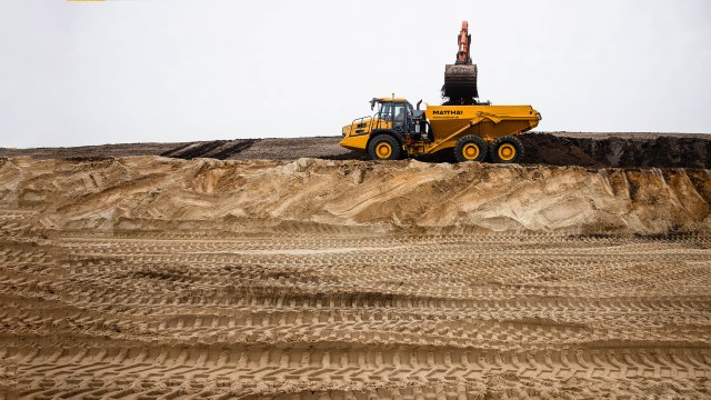 A yellow dump truck on a sand hill.