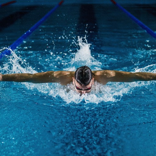A swimmer is utilizing psychology for success while swimming in a pool at night.
