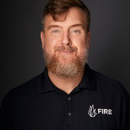 A man with a beard wearing a black polo shirt.