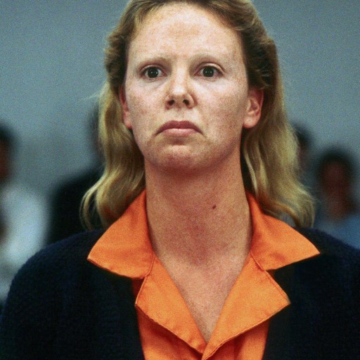 A woman in an orange shirt standing in front of a crowd.