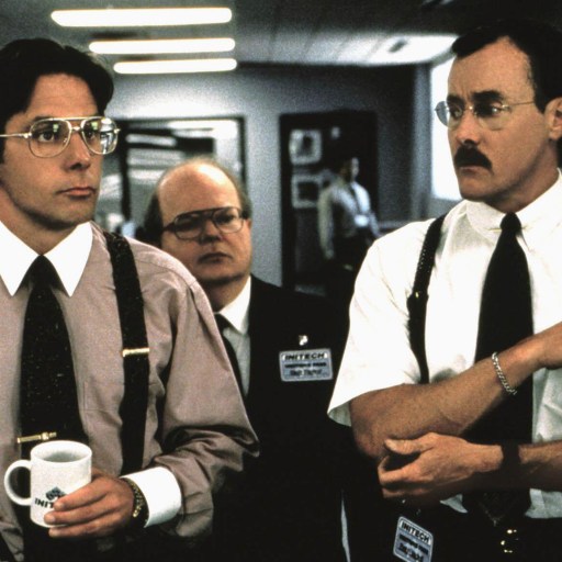 Two men in suspenders standing next to each other in an office, possibly enduring the presence of a bad boss.