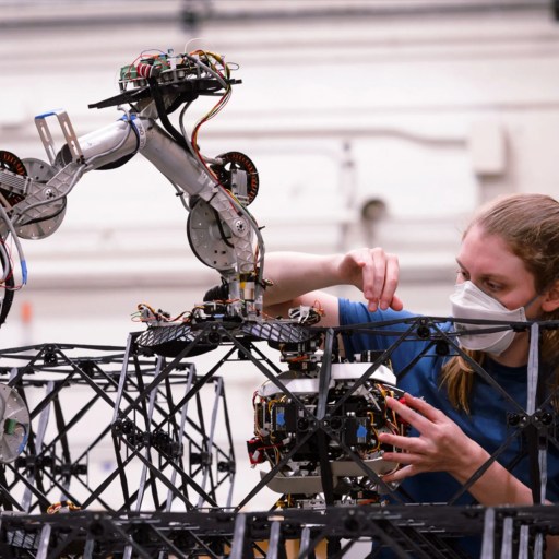 A woman is working on a robot in a factory.