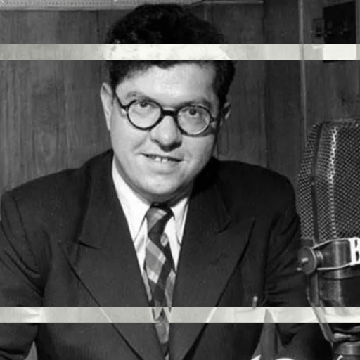 Man in a suit posing with a vintage BBC Big Bang 75 microphone.