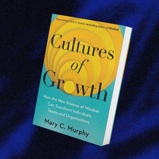 A book titled "Cultures of Growth" by Mary C. Murphy lying on a dark blue fabric surface.