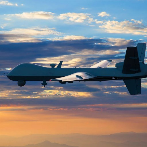 A drone flying in the sky at sunset with clouds in the background.