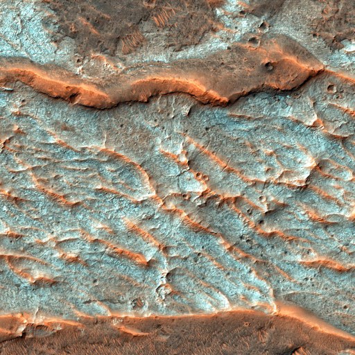 Aerial image of a Martian landscape with rough, textured surface featuring blue and reddish-brown hues marked by undulating ridges and valleys.