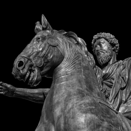 Bronze statue of a bearded man embodying stoicism, riding a horse with one arm extended forward, set against a black background.