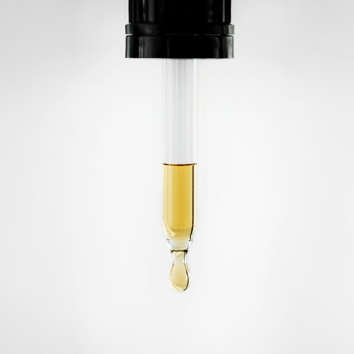 Close-up of a dropper releasing a drop of yellow liquid, showcasing the foundation of chemistry against a pristine white background.