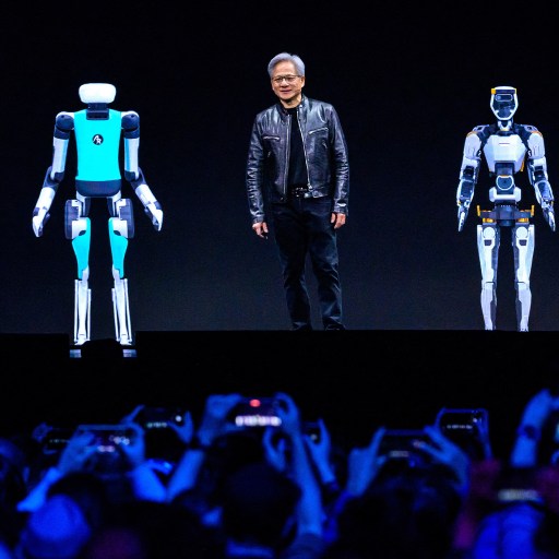 A person stands on stage with four humanoid robots, powered by NVIDIA technology, presenting to an eager audience.