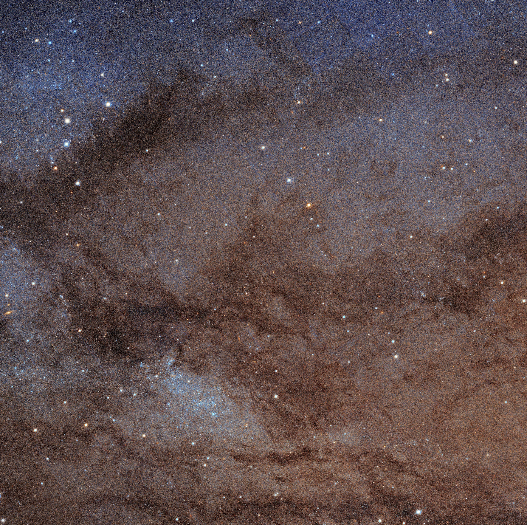 A star-filled night sky showcases the largest galactic mosaic, where interstellar dust and gas form dark, cloud-like patterns against a backdrop of bright, scattered stars.