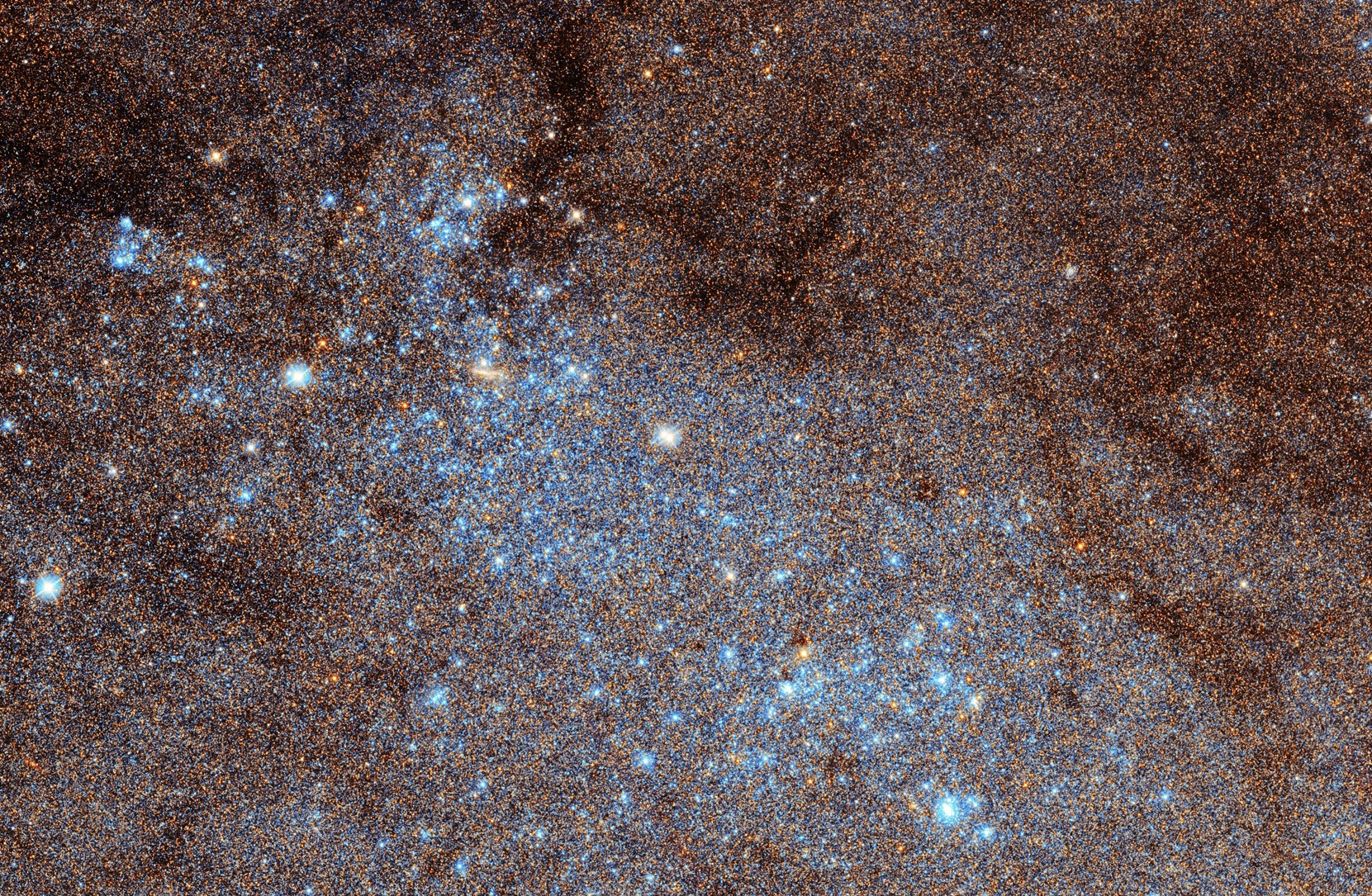 A dense cluster of blue and orange stars forms a vibrant, speckled pattern against the dark space backdrop, reminiscent of the largest galactic mosaic.