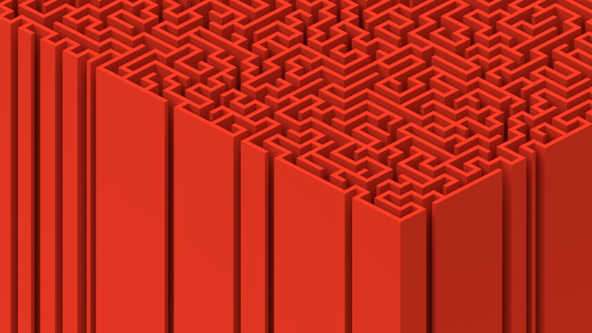Intricate 3D red maze with vertical walls, viewed from an angle, showing complex pathways and geometric design.