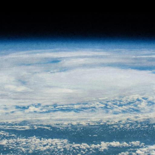 From a vantage point reminiscent of Carl Zimmer's explorations, an aerial view captures a massive swirling cloud formation over Earth, resembling a hurricane or cyclone against the infinite darkness of space.