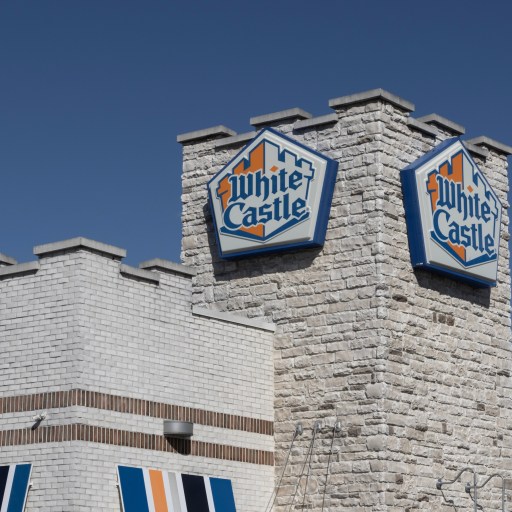 White Castle restaurant building with logo signs on a stone tower stands proudly against a clear blue sky, embodying an evergreen business model that continues to thrive.