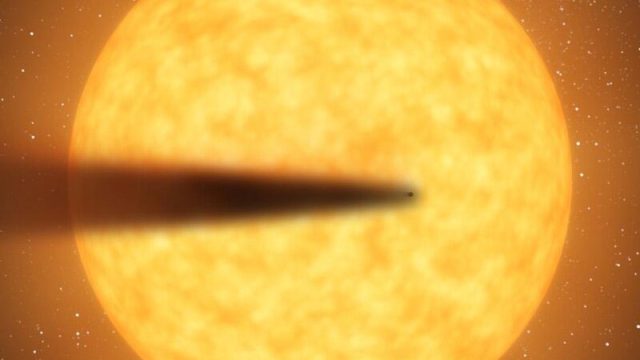 A glowing orange planet casts a shadow in space amid a backdrop of stars.