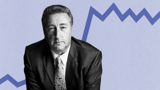 Barry Ritholtz, a man in a suit and tie, stands confidently before a blue zigzag line on a light backdrop.