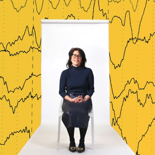 A woman sits on a chair against a white backdrop, with yellow graphics of brain wave patterns in the background.