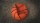 A deflated basketball lies on rough, textured ground.
