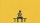 A person sits alone on a bench against a yellow background, looking down at a smartphone.