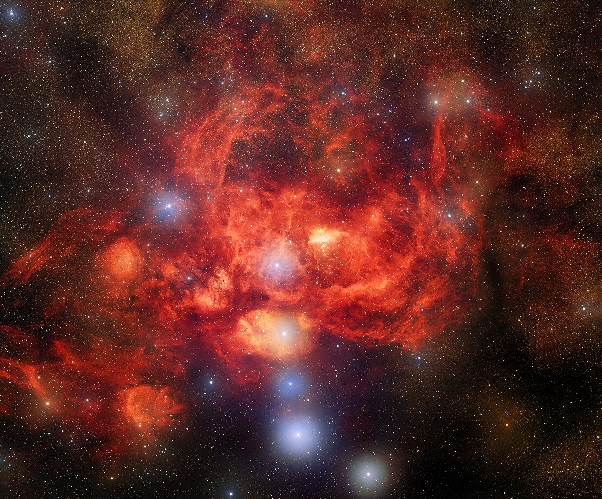 A bright, red nebula surrounded by numerous stars in deep space, with glowing clouds of gas and dust illuminated throughout the formation—captured in stunning detail by JWST and Hubble near the remarkable cluster Pismis 24.
