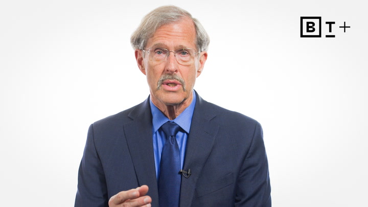 An older man in a suit and tie speaks while gesturing, with the letters "BT+" displayed in the top right corner against a white background.