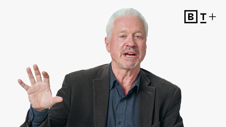 An older man with white hair and a beard, wearing a dark blazer and navy shirt, speaks with his hand raised. The BT+ logo appears in the top right corner.