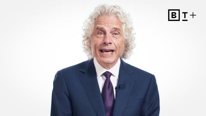 A man with curly gray hair in a blue suit and purple tie speaks in front of a white background with a BT+ logo in the top right corner.