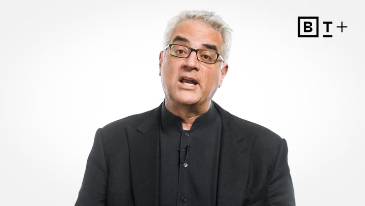 A middle-aged man with gray hair and glasses, wearing a black suit and shirt, speaks against a plain white background with a "BT+" logo in the top right corner.