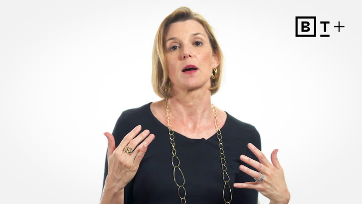 A woman with short blonde hair wearing a black top and gold chain necklace gestures with her hands while speaking. A BT+ logo is visible in the top right corner.