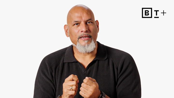 A bald man with a white goatee wears a black collared shirt and gestures with his hands; a "BT+" logo appears in the top right corner.