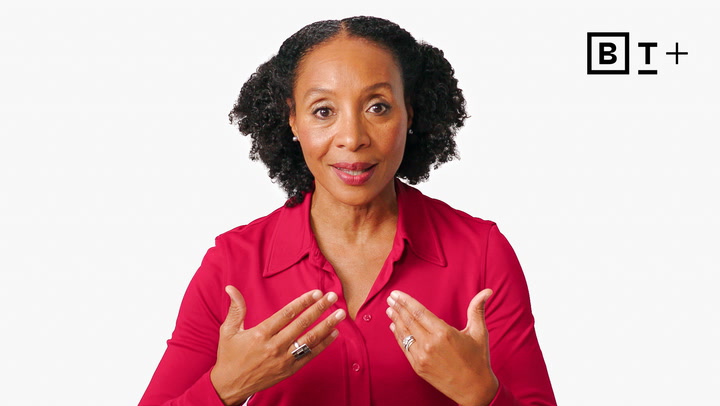 A woman in a red shirt gestures with both hands raised to her chest while looking at the camera. A black and white "BT+" logo appears in the top right corner.