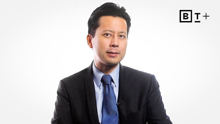 A man in a suit and blue tie sits against a white background with the BT+ logo in the top right corner.